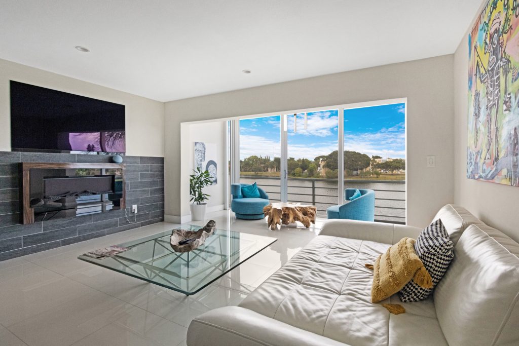 Bright living room with large windows overlooking river and sky.