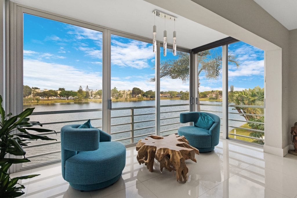 Bright living room with large windows overlooking a river and blue sky.