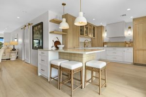 Bright, contemporary kitchen featuring light wood cabinetry and a central island with seating.