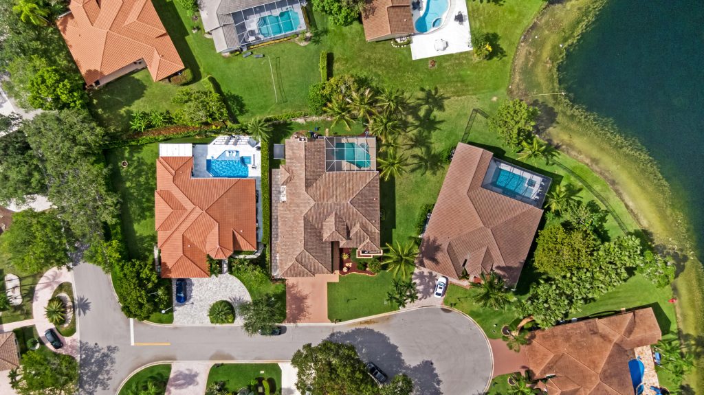 Aerial view of upscale houses with pools and water access in a gated community.