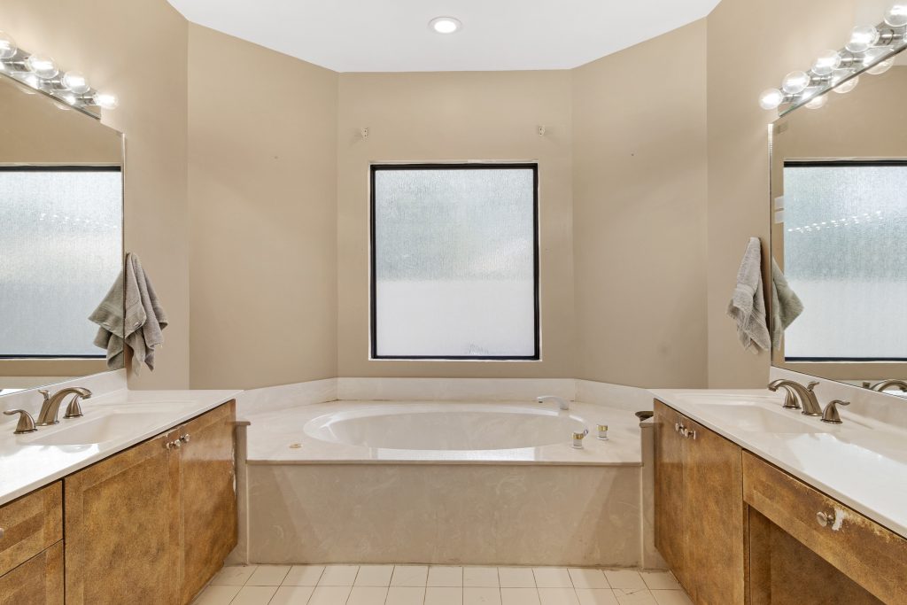 Bathroom with double sinks, large mirror, and bathtub in neutral tones.