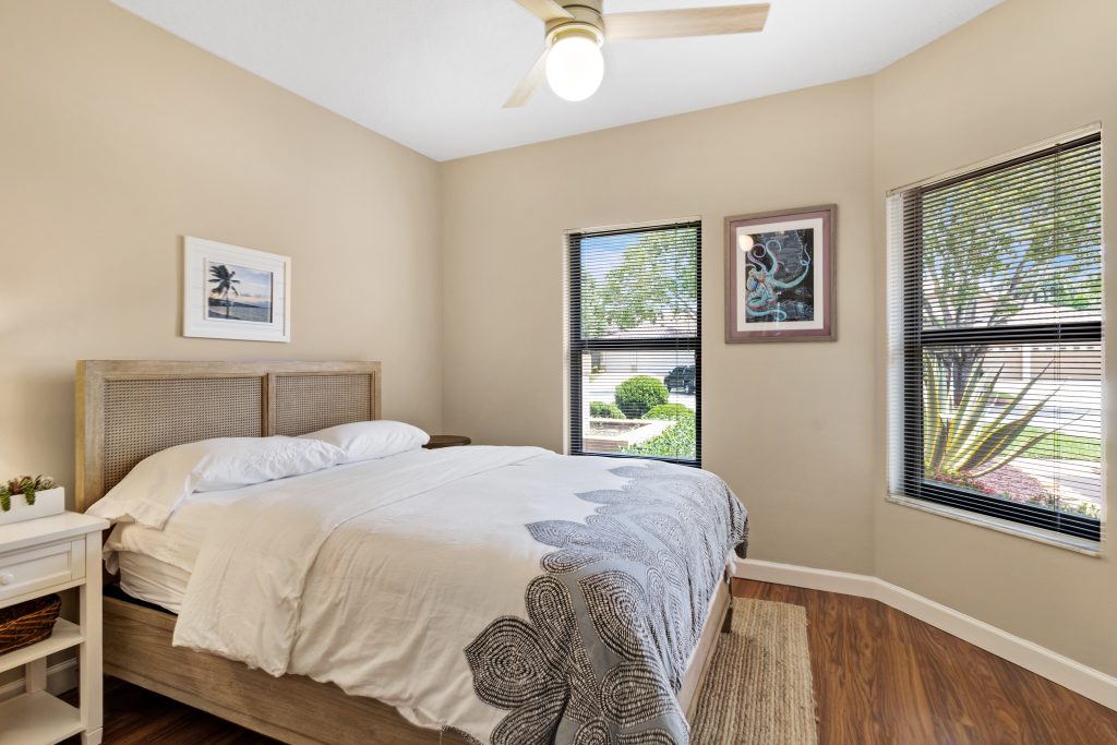 Bright bedroom with large windows, neutral decor, and a comfortable bed.