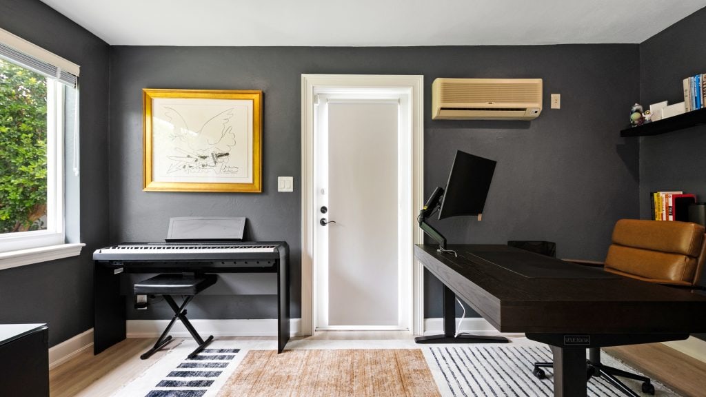 Contemporary home office with piano, desk, and wall art.