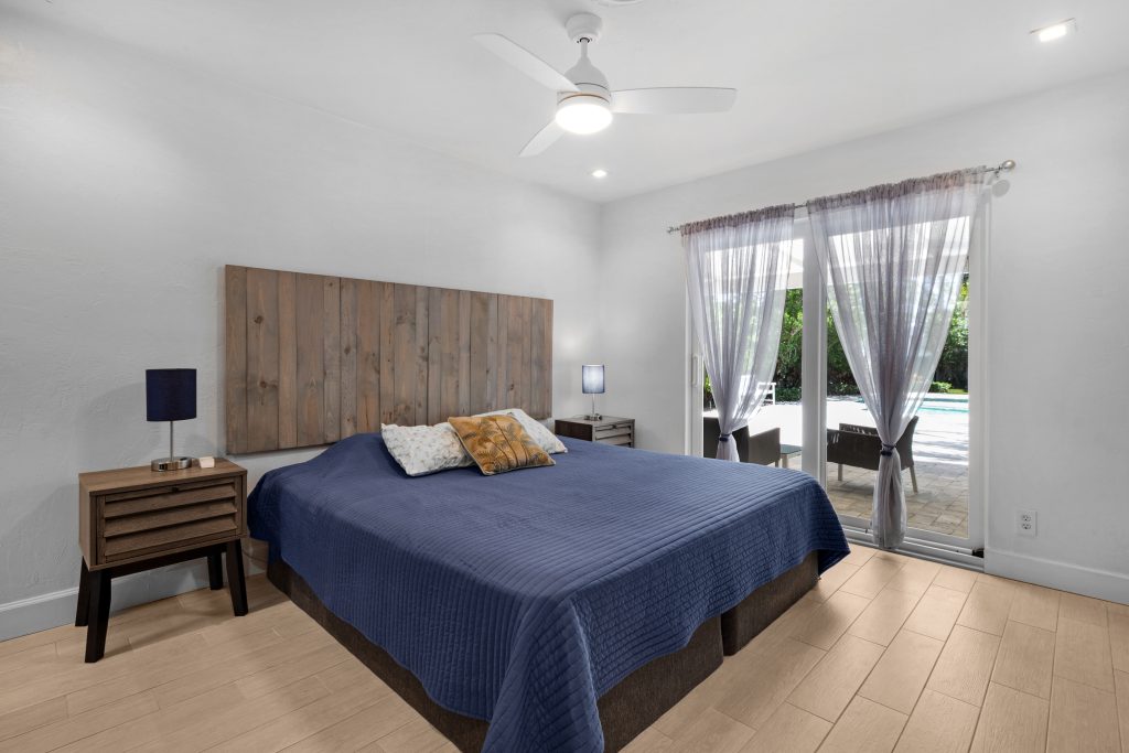 Bright bedroom with large windows, wooden headboard, and minimalist decor.