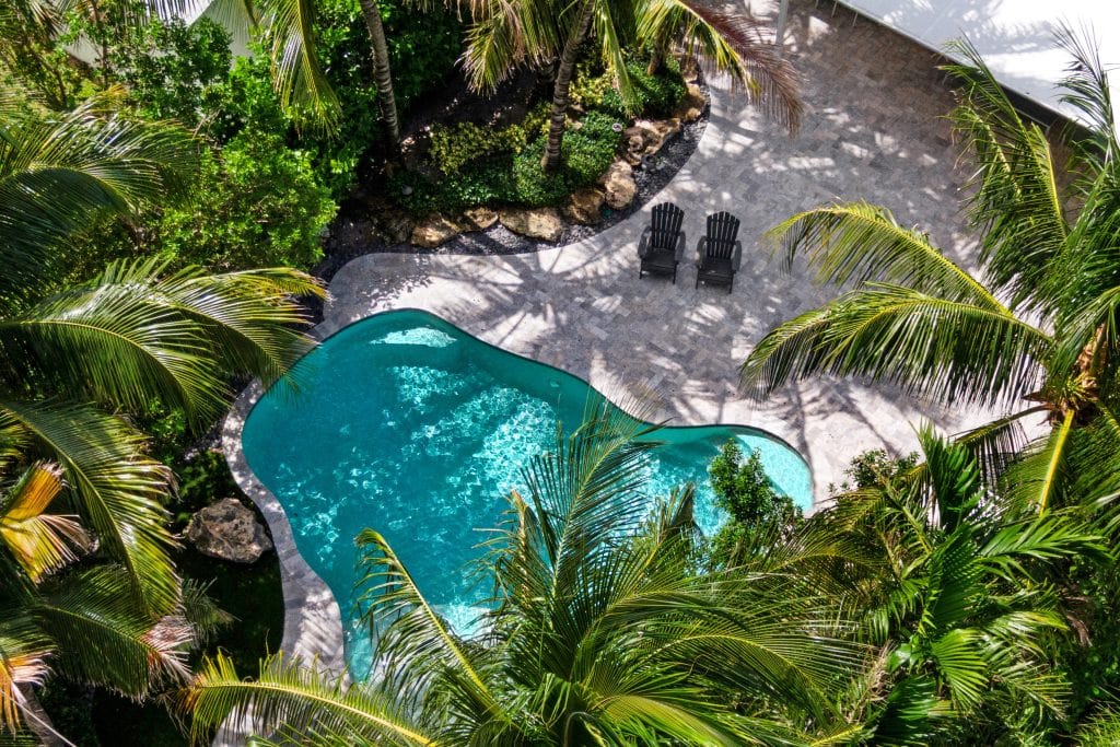 Aerial view of a tropical backyard with a pool and lounge chairs.