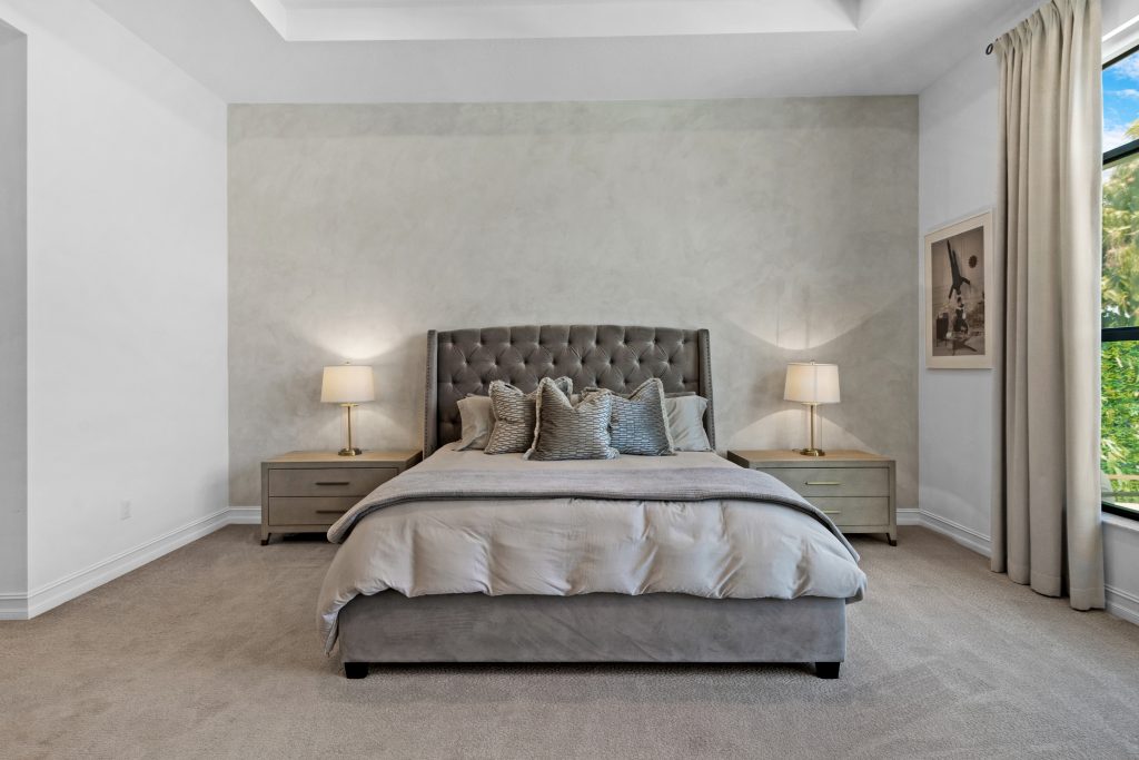 Elegant bedroom with a large bed, nightstands, and natural light from windows.