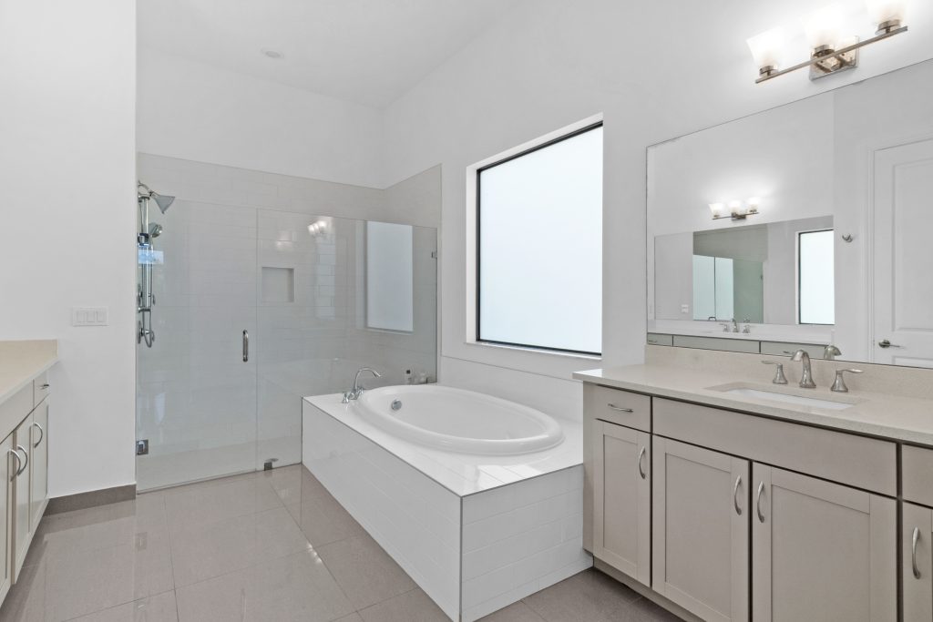 Spacious bathroom with bathtub, shower, and large window for natural light.