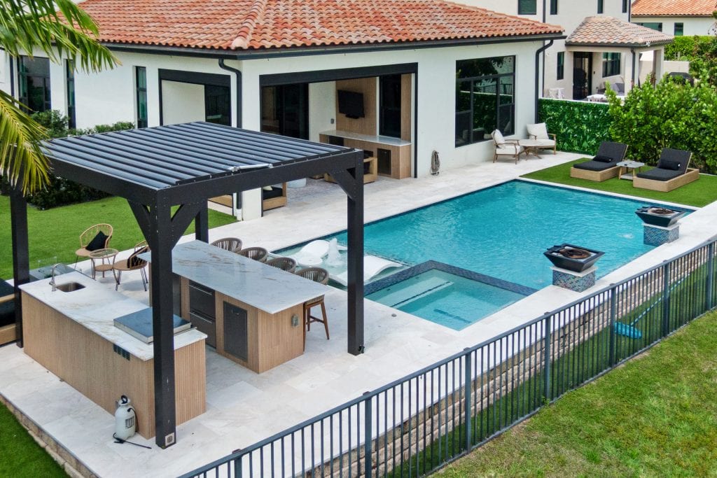Modern backyard pool with outdoor kitchen and lounge area.