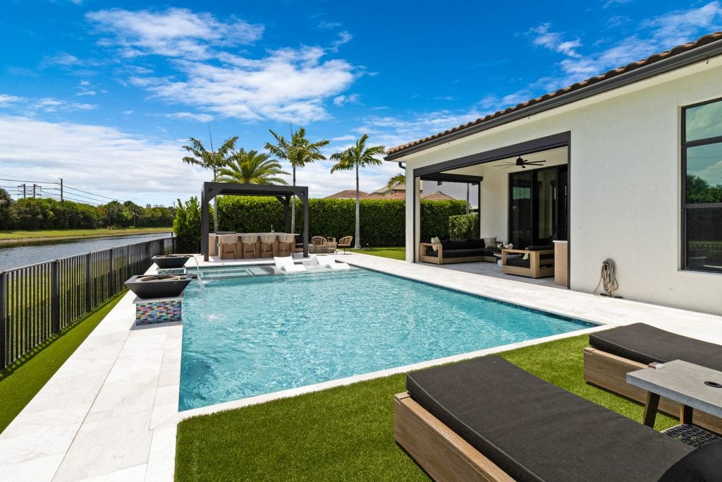 Modern backyard with pool, lounge chairs, and outdoor seating area.