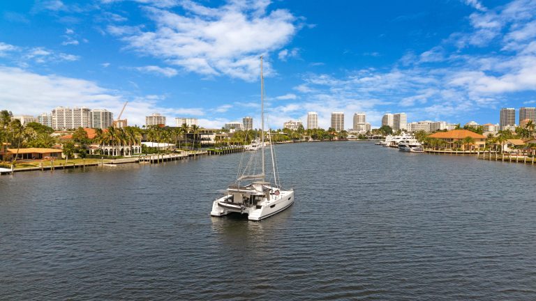 Luxury yacht sailing on calm water with city skyline in background.