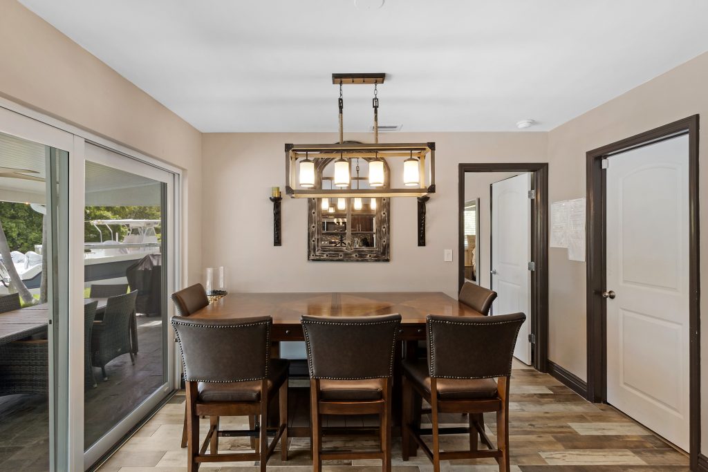 Bright dining room with large windows, wooden table, and stylish chandelier.