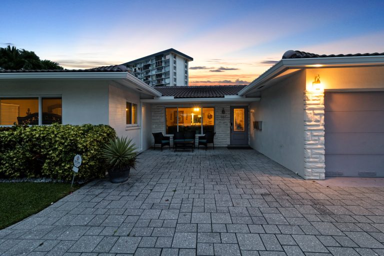 Contemporary house exterior with driveway and warm lighting at sunset.