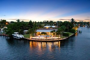 Elegant waterfront home with dock and boat in a tropical setting.