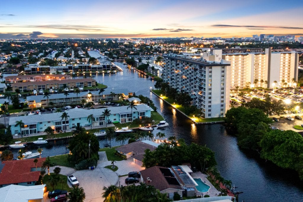 Aerial view of a waterfront city with high-rise buildings and canals at sunset.
