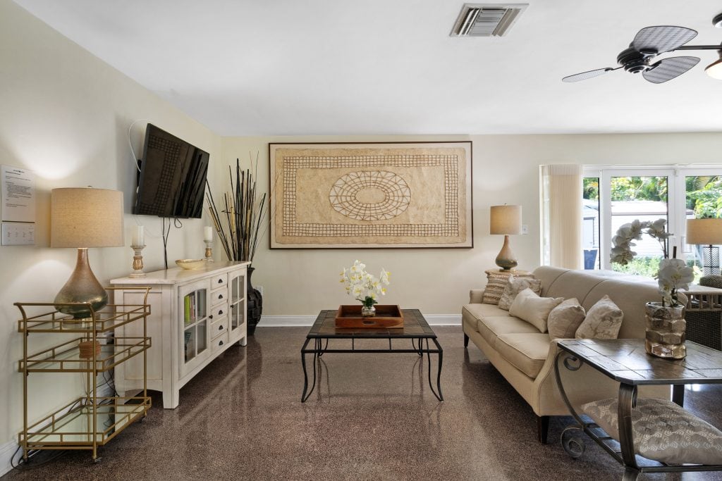 Spacious living room with beige sofa, wall-mounted TV, and decorative artwork.