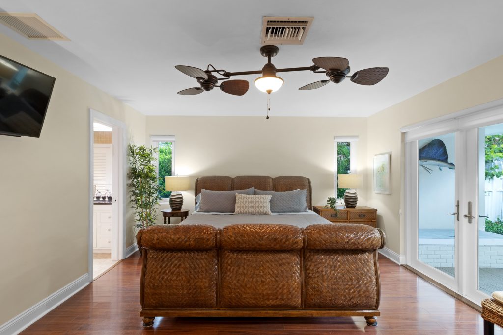 Bright bedroom with large windows, ceiling fan, and cozy bed setup.