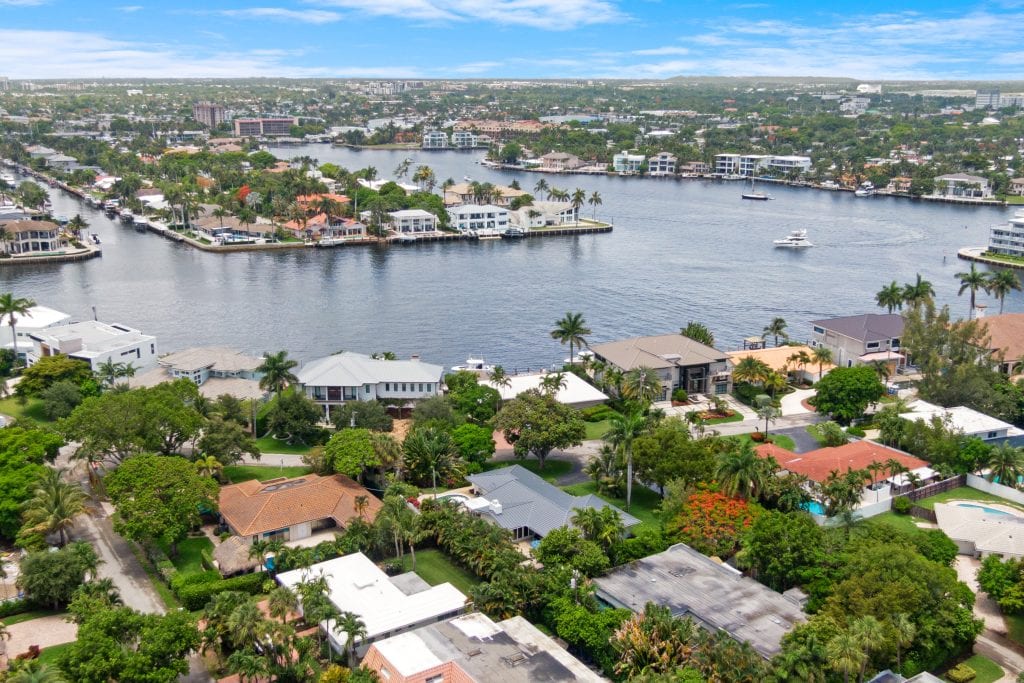 Aerial view of waterfront homes and boats in a lush neighborhood.