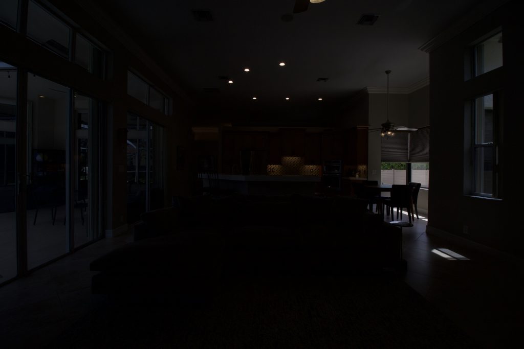 Dark interior of a modern home with large windows and dining area, HDR real estate photography.