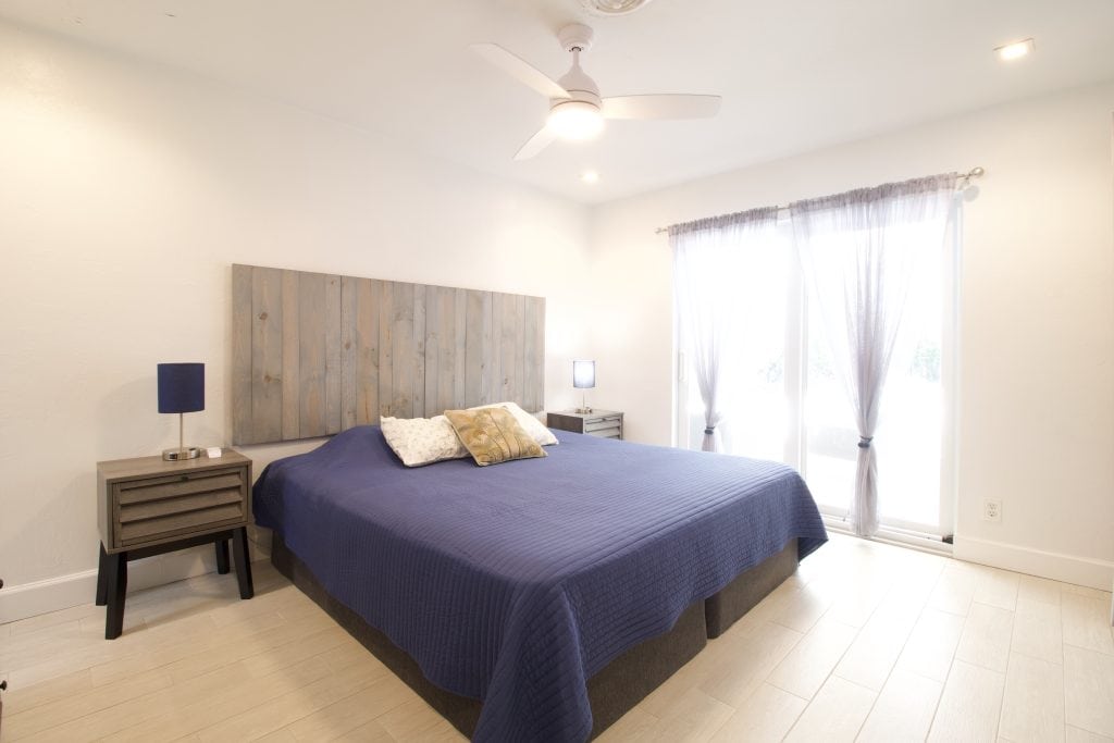 Bright bedroom with large windows, blue bedding, and minimalist decor.