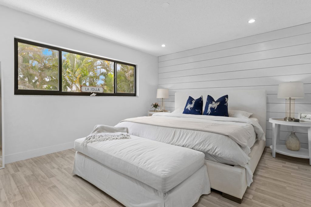 Bright, airy bedroom with large window and white decor.