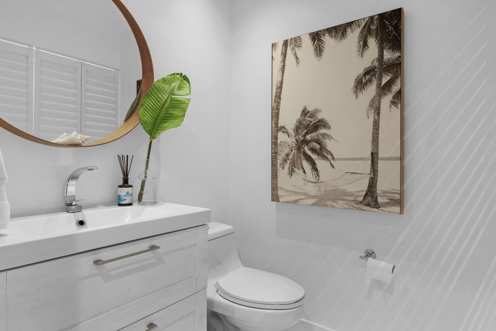 Contemporary bathroom with tropical decor and ocean-themed artwork.