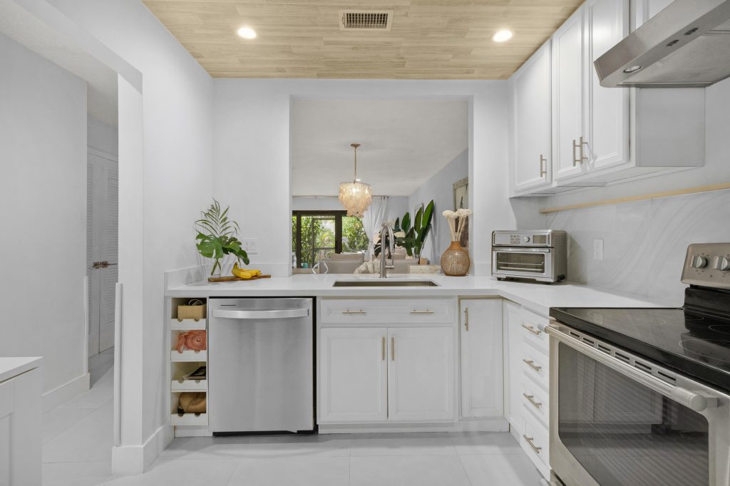 Bright modern kitchen with white cabinets and stainless steel appliances.