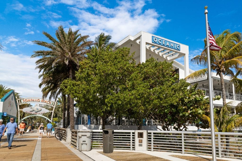 Oceanic building in Pompano Beach with palm trees and blue sky.