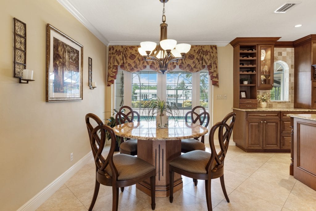 Bright dining room with round table, chandelier, and large windows.