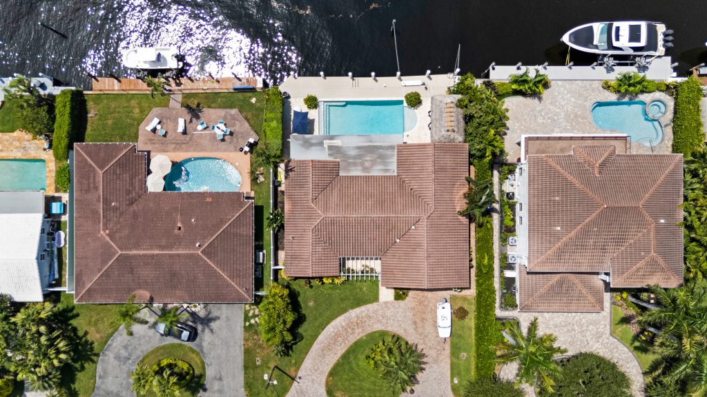 Aerial view of three houses with pools in Pompano Beach, Florida.