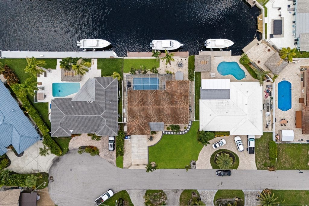 Aerial view of waterfront homes with pools and boats in Pompano Beach.