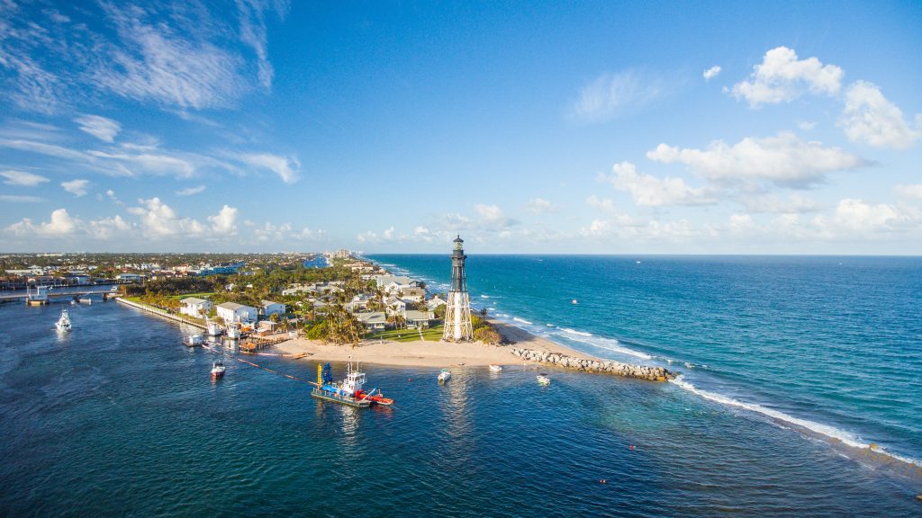 Scenic view of Pompano Beach lighthouse and ocean under blue sky.