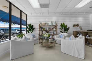 Modern interior with white sofas, glass table, and decorative plants.