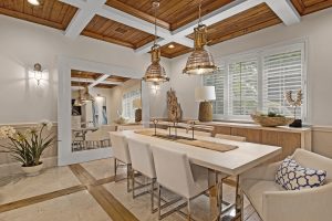 Bright coastal dining room with wooden ceiling and large windows.