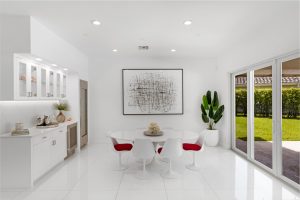 Bright modern dining room with white furniture and large sliding glass doors.
