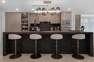 Contemporary kitchen with black marble island and four bar stools.