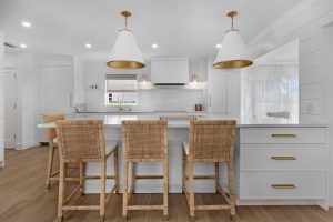 Bright modern kitchen with white cabinets, gold pendant lights, and a central island with seating.