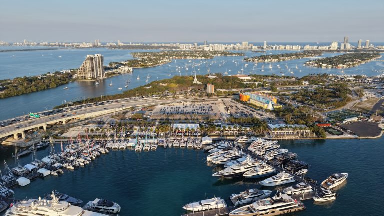 Aerial view of a South Florida marina with yachts and city skyline.