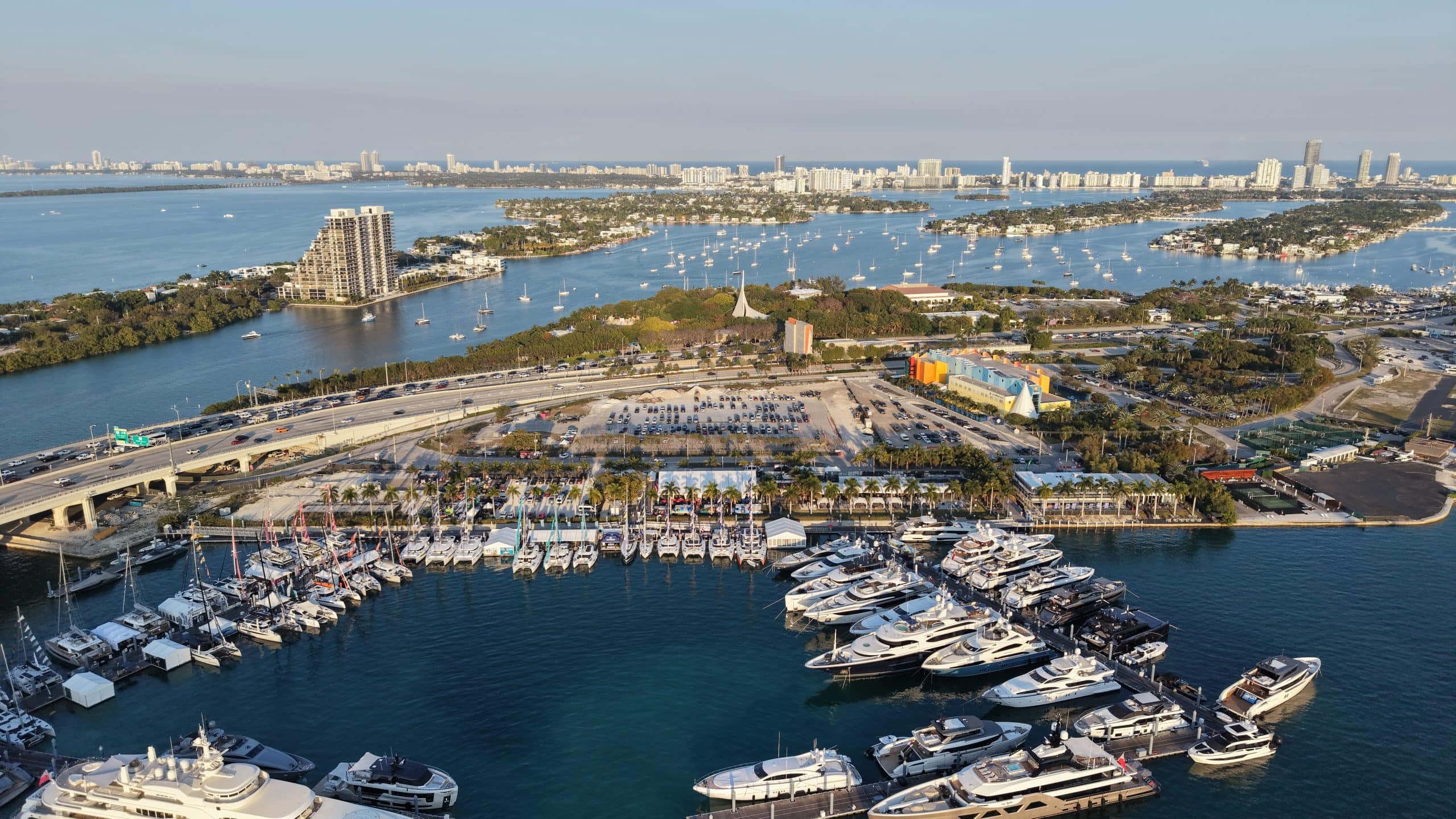Aerial view of a South Florida marina with yachts and city skyline.